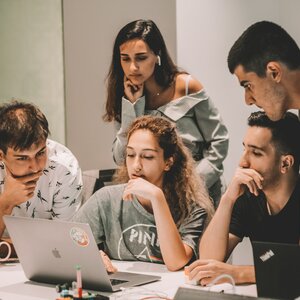 5 studenten zitten samen aan de laptop