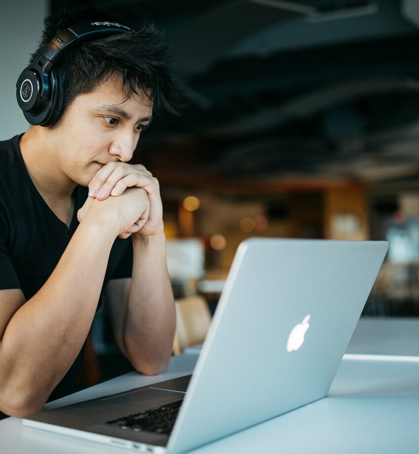 jongen met hoofdtelefoon kijkt naar laptop