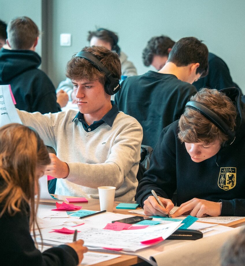 groep studenten schetst prototypes op papier, de twee studenten op de voorgrond dragen een hoofdtelefoon