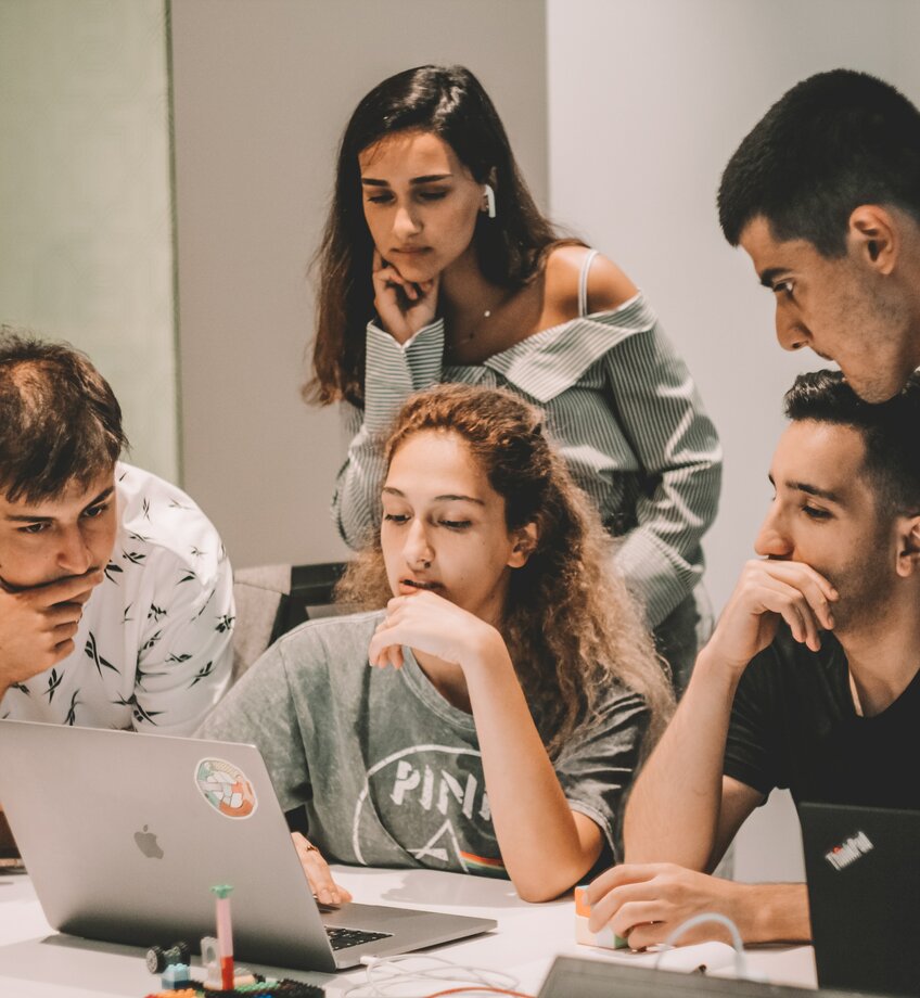 5 studenten zitten samen aan de laptop