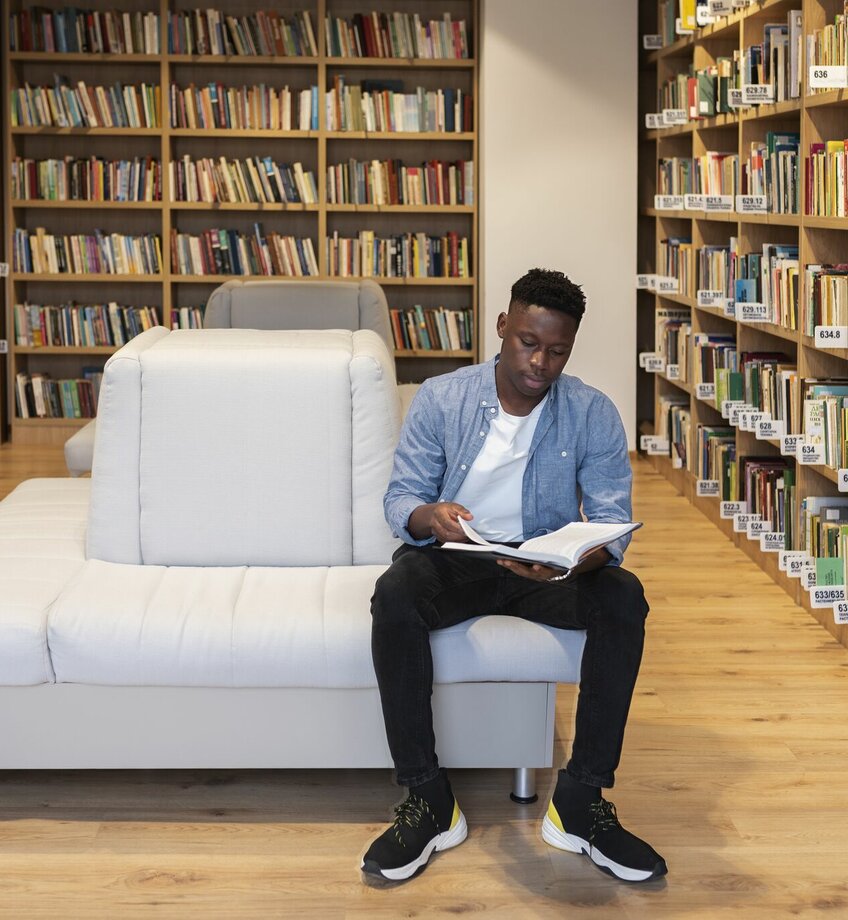 Student leest boek in bibliotheek