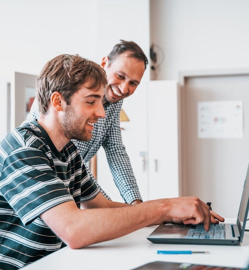 Student aan laptop en docent