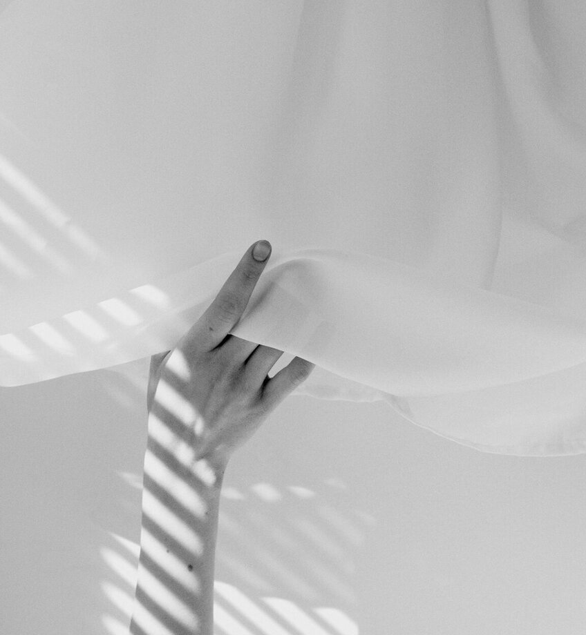Hand lifts white curtain