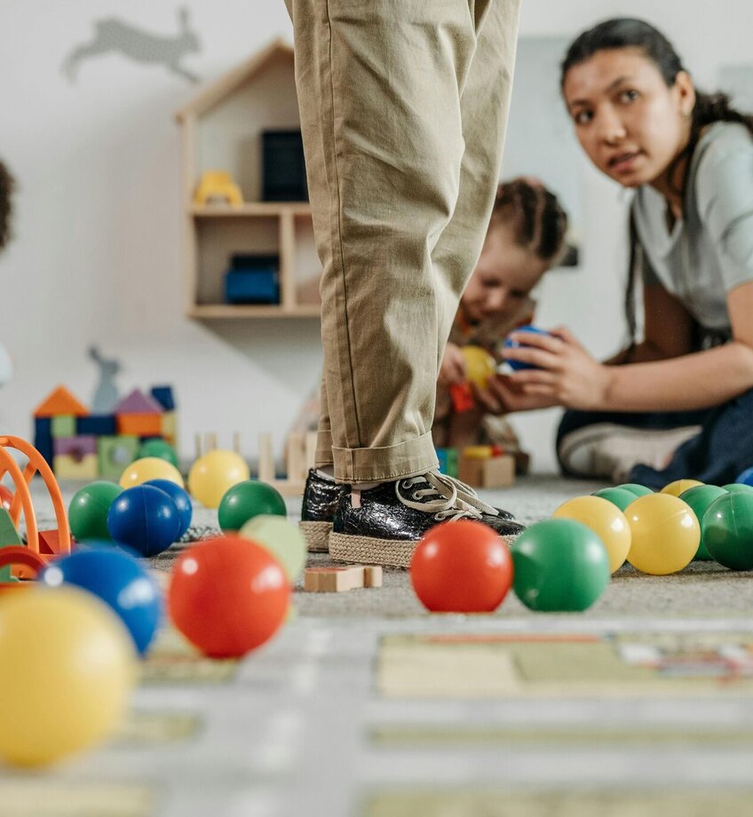 Nursery children playing with teacher in the classroom