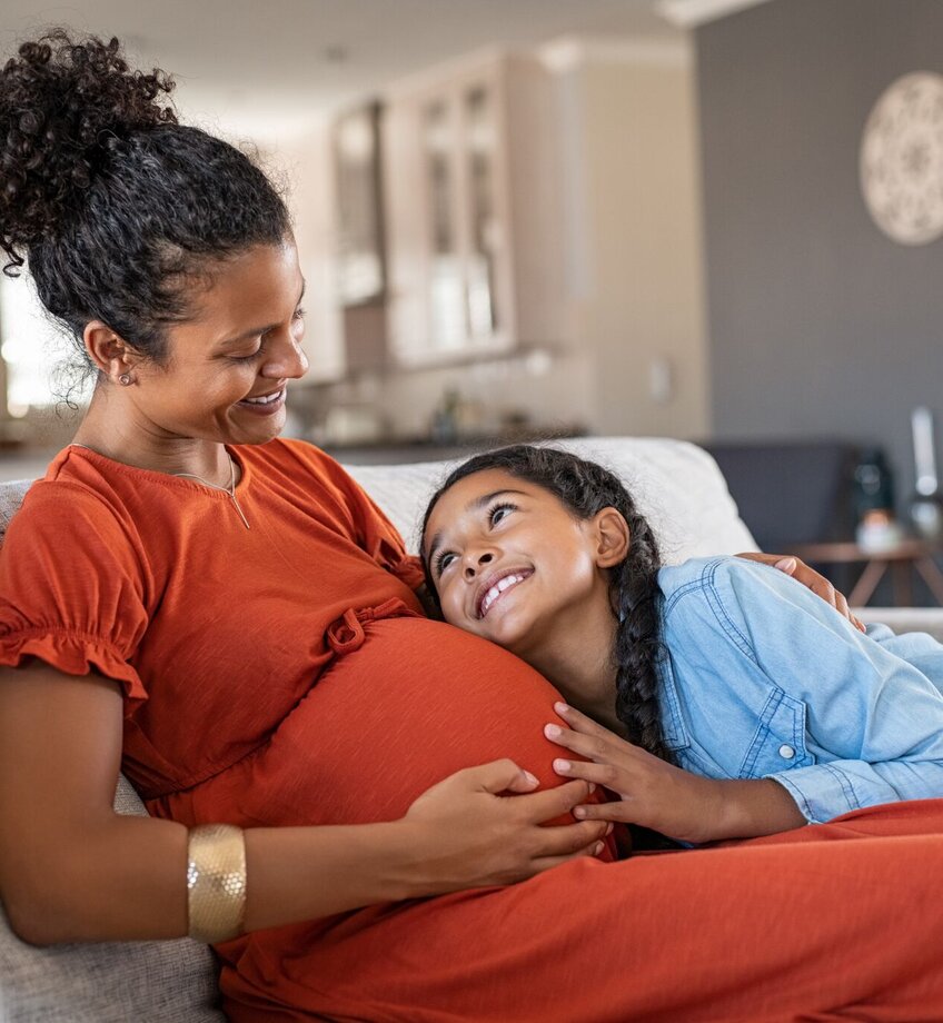 Happy lovely daughter hugging pregnant mother