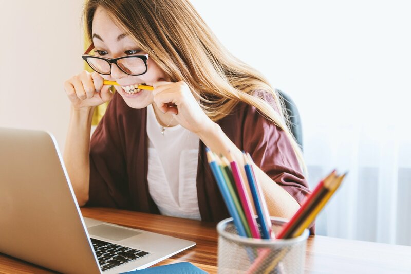 student voor laptop bijtend op potlood