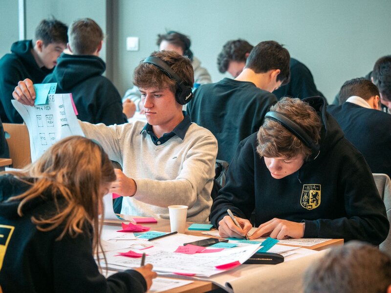 groep studenten schetst prototypes op papier, de twee studenten op de voorgrond dragen een hoofdtelefoon