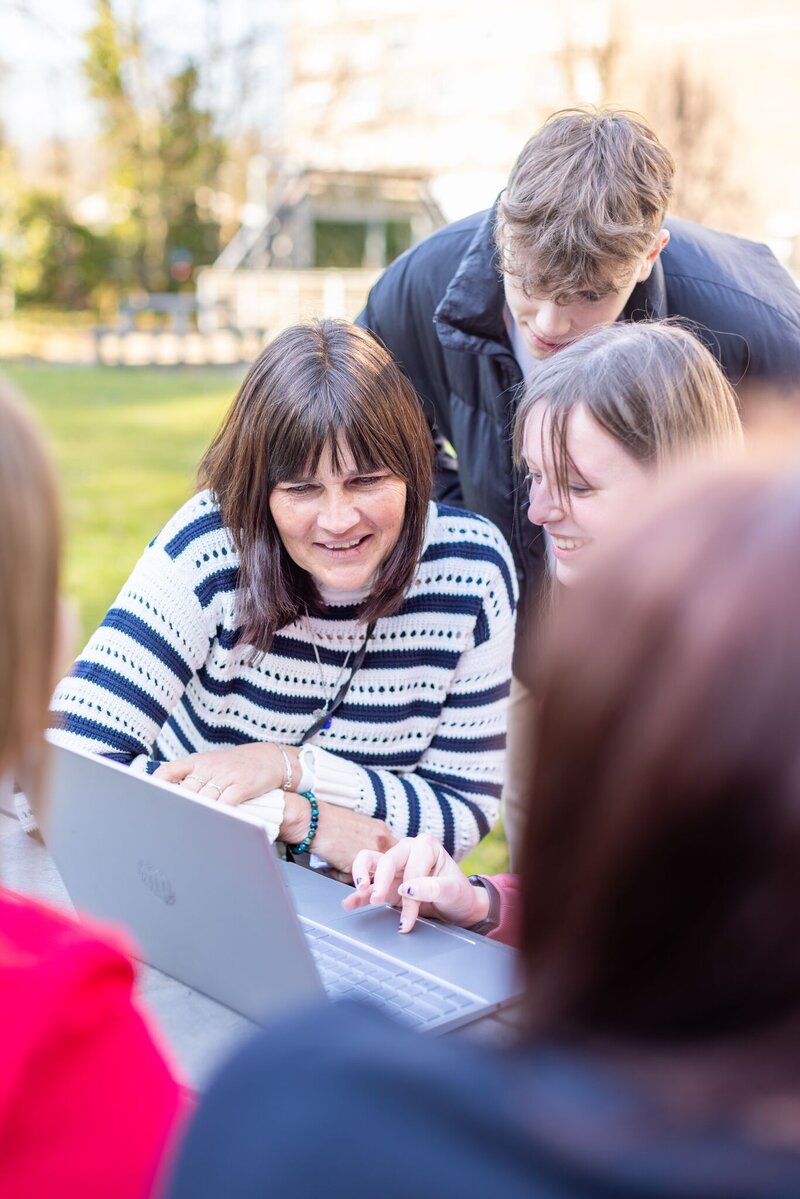 Studenten en collega rond een laptop