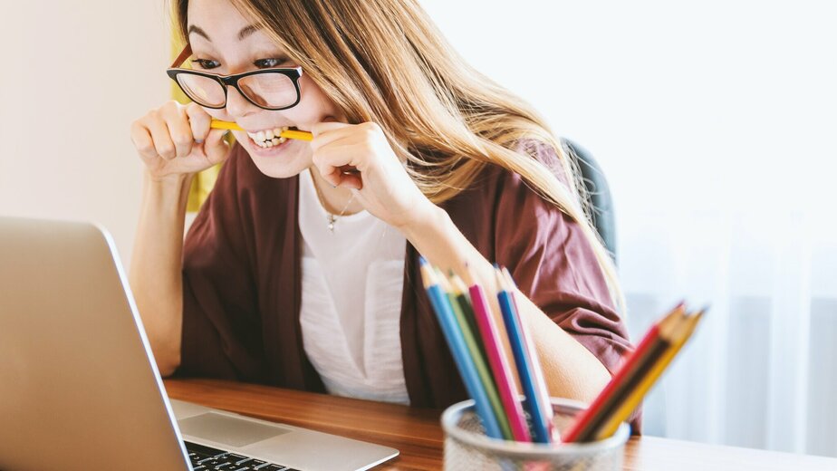 student voor laptop bijtend op potlood