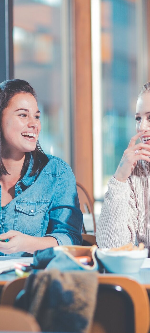 Drie studentes lachend aan een tafel