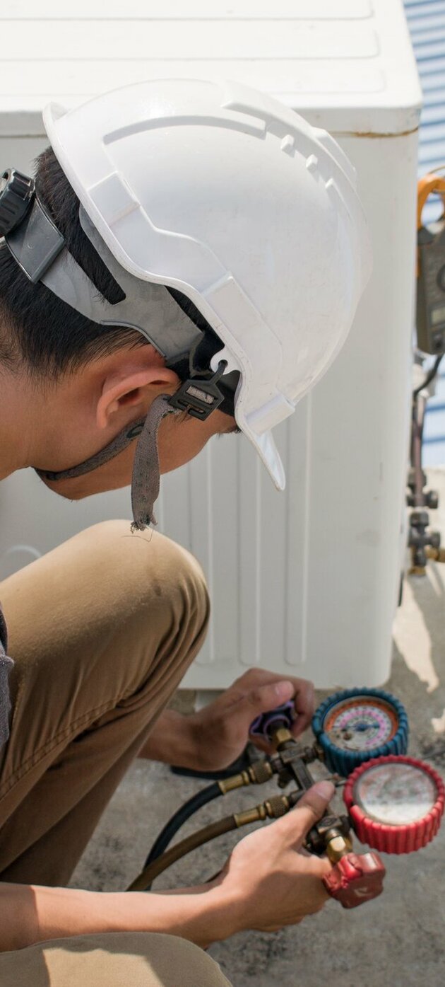 Man met helm werkt aan koelinstallatie