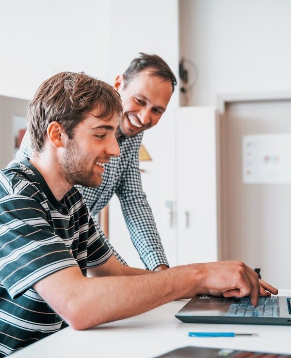 Student aan laptop en docent